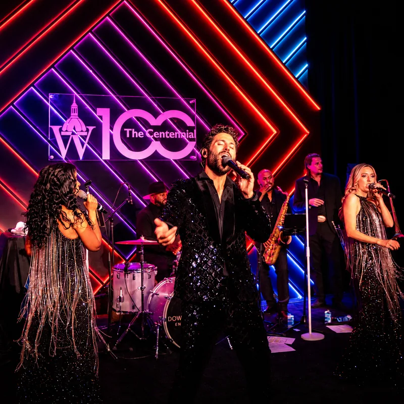 A programmed LED chevron wall in red, magenta, and blue behind a live band at the Wilmer Eye Institute centennial for Johns Hopkins, Baltimore Marriott Waterfront, by EventPro