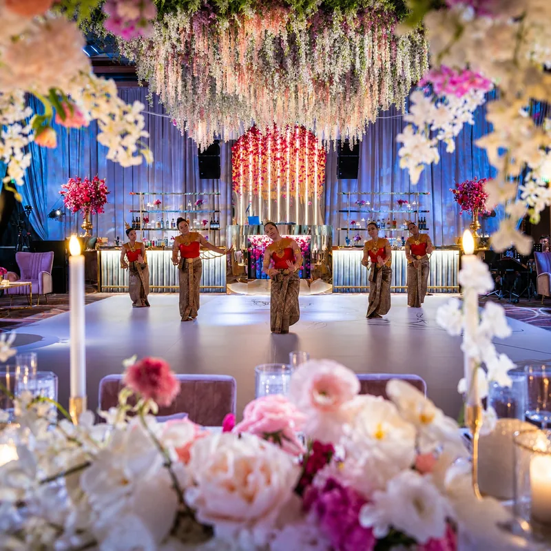 Blue wash across the drape, a backlit bar, and an uplit floral installation over the dance floor at a wedding reception at the Four Seasons Baltimore by EventPro