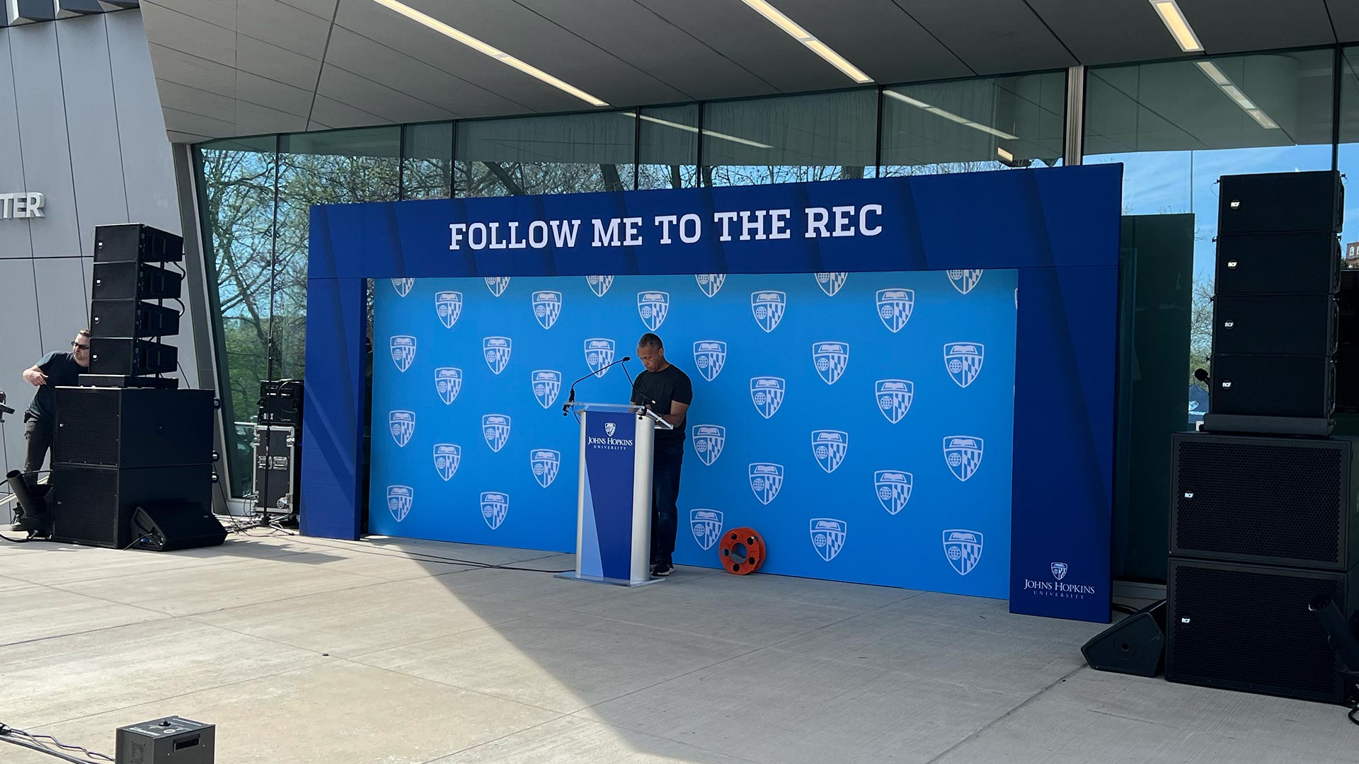 Full outdoor stage at the Follow Me to the Rec grand opening, EventPro custom backdrop, branded podium, and cold spark effects, Johns Hopkins University Baltimore