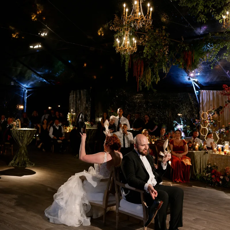 Pin spots on the couple, a chandelier hung in greenery, and blue side wash at a tented wedding reception at a private residence in Baltimore by EventPro