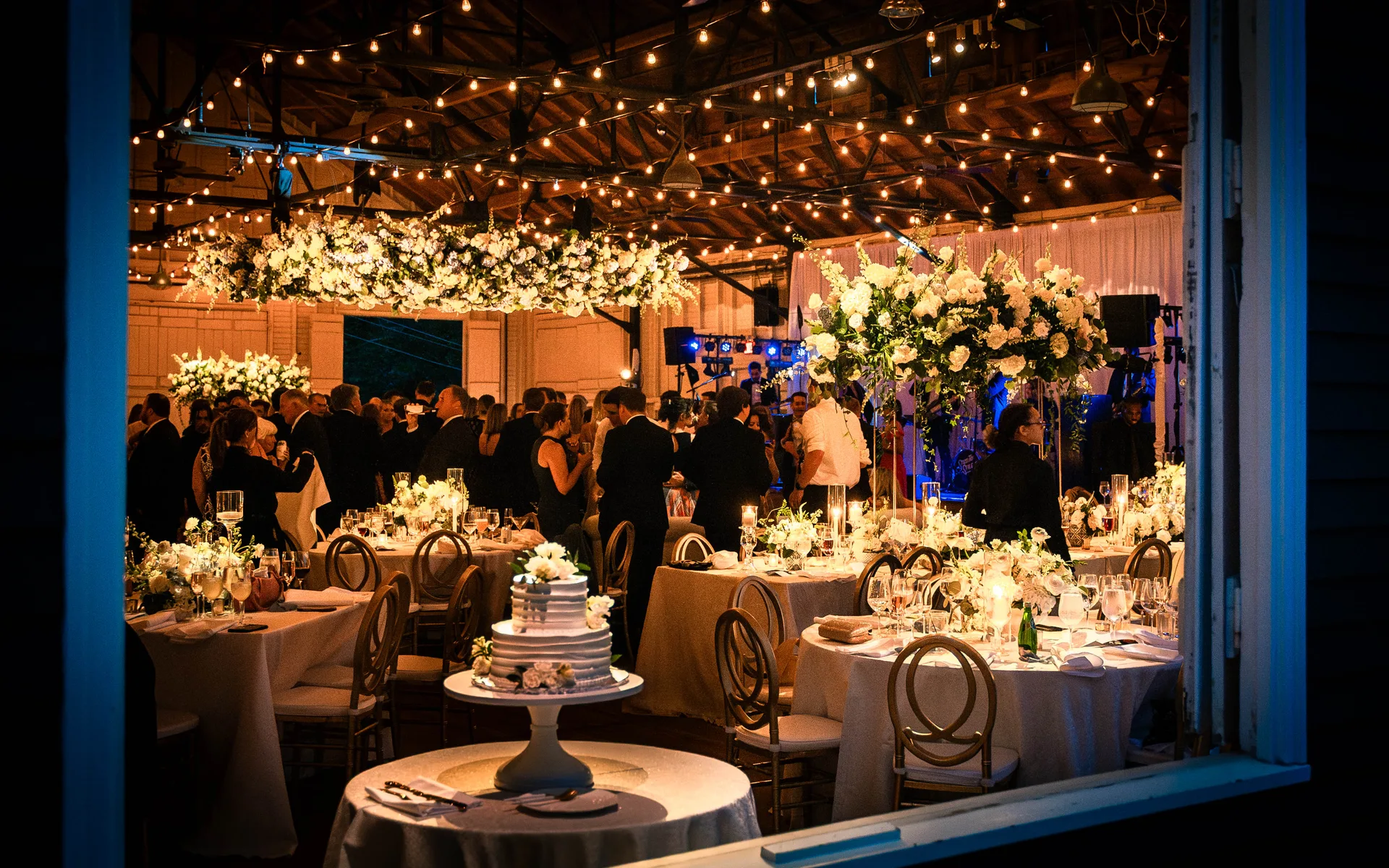 Sherwood Forest wedding reception, string lights overhead, cherry blossom tree installation, tall floral centerpieces, wedding cake, EventPro event production Maryland