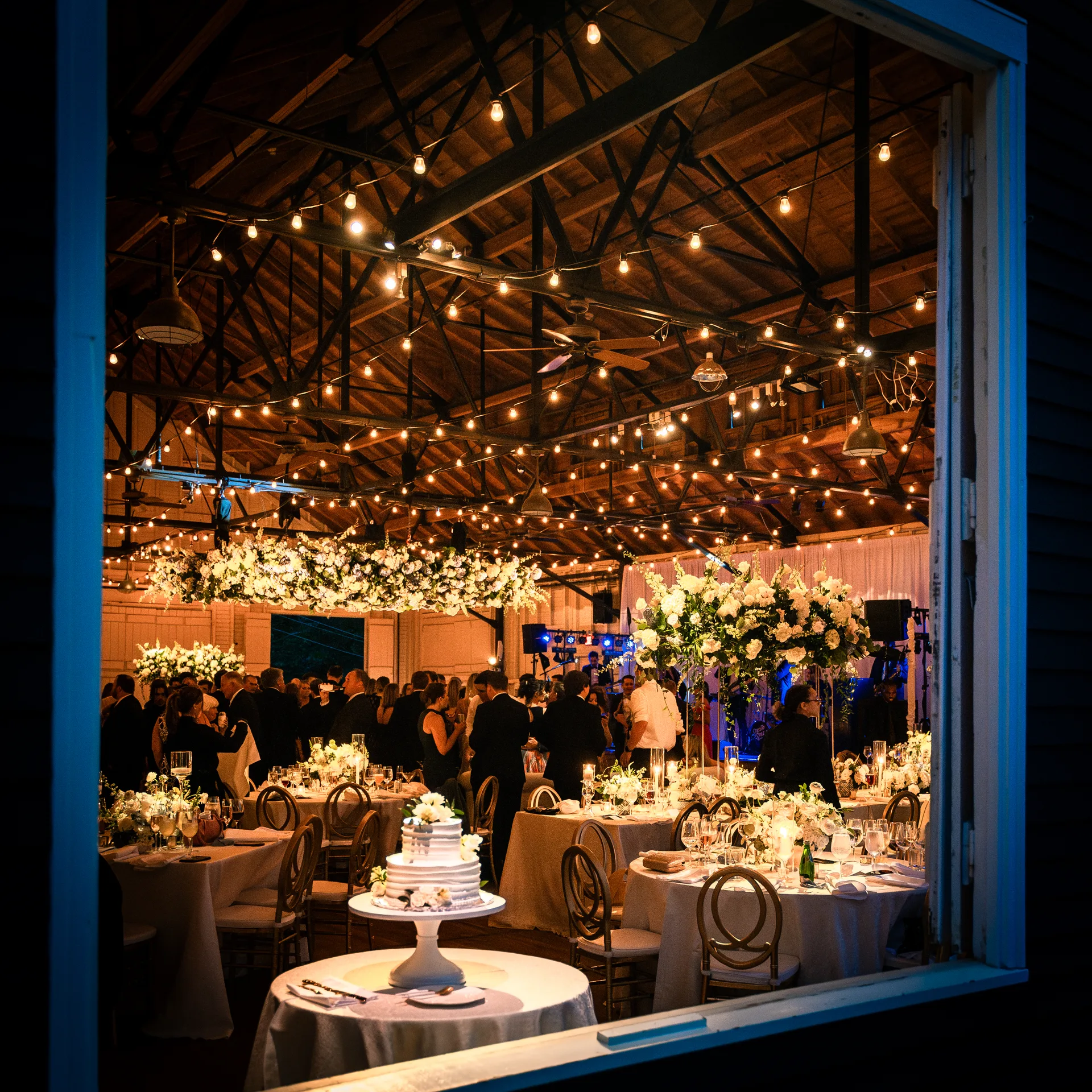Sherwood Forest wedding reception, string lights overhead, tall floral centerpieces, guests on dance floor, EventPro event production Maryland