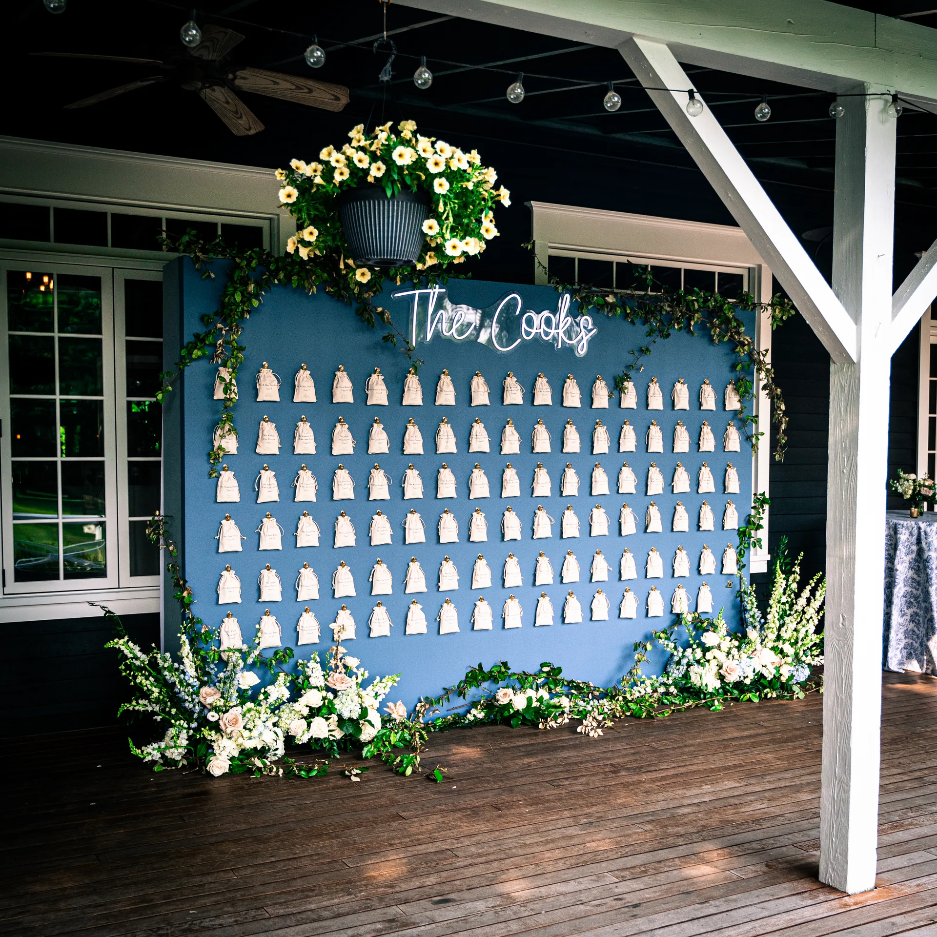 Custom seating chart installation at Sherwood Forest wedding, blue wall with neon The Cooks sign, escort card display, fresh floral frame, EventPro décor Sherwood Forest Maryland