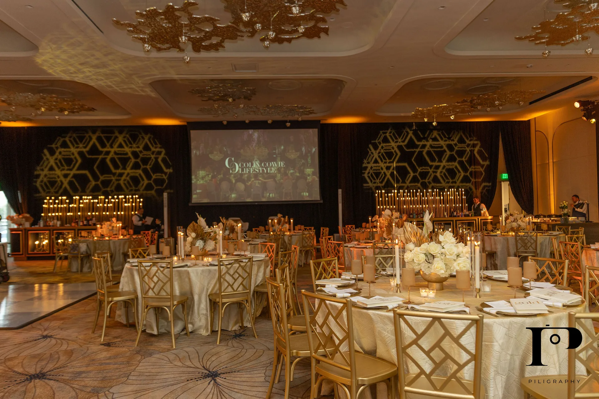 Colin Cowie Lifestyle NACE South Florida gala at Pier 66 Fort Lauderdale, full ballroom during setup, black and gold pipe and drape, custom bar with Solene candle array, gold chiavari chairs, EventPro event production Fort Lauderdale Florida