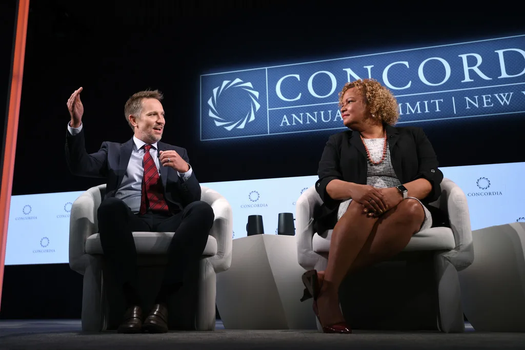 Two panelists in discussion at Concordia Annual Summit 2021, Concordia LED wall sign in background, white armchair seating, EventPro furnishings and scenic production New York