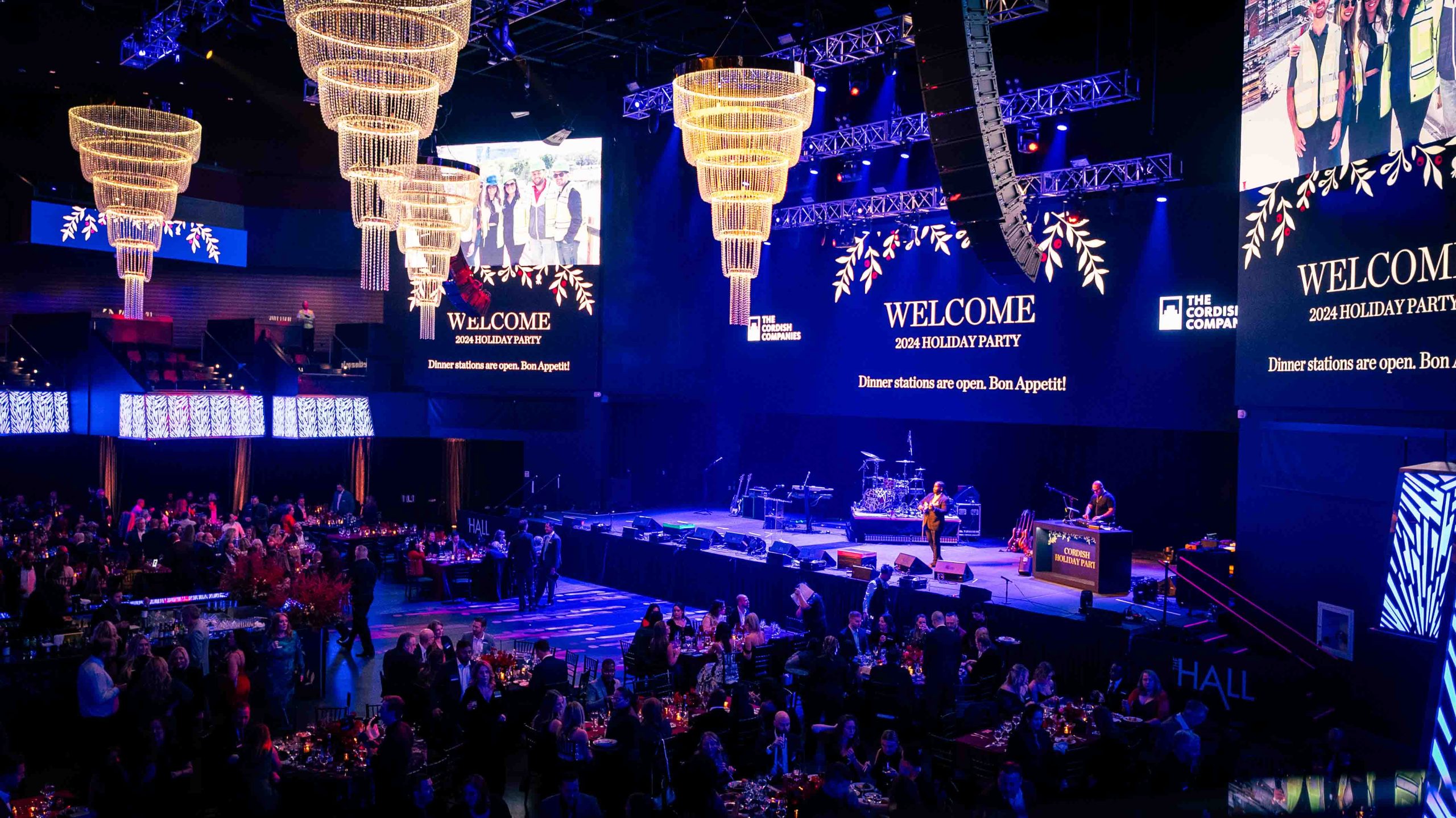 Full crowd at the Cordish Companies 2024 Holiday Party, live band on stage, crystal chandeliers overhead, LED video walls, Live! Casino Maryland, EventPro