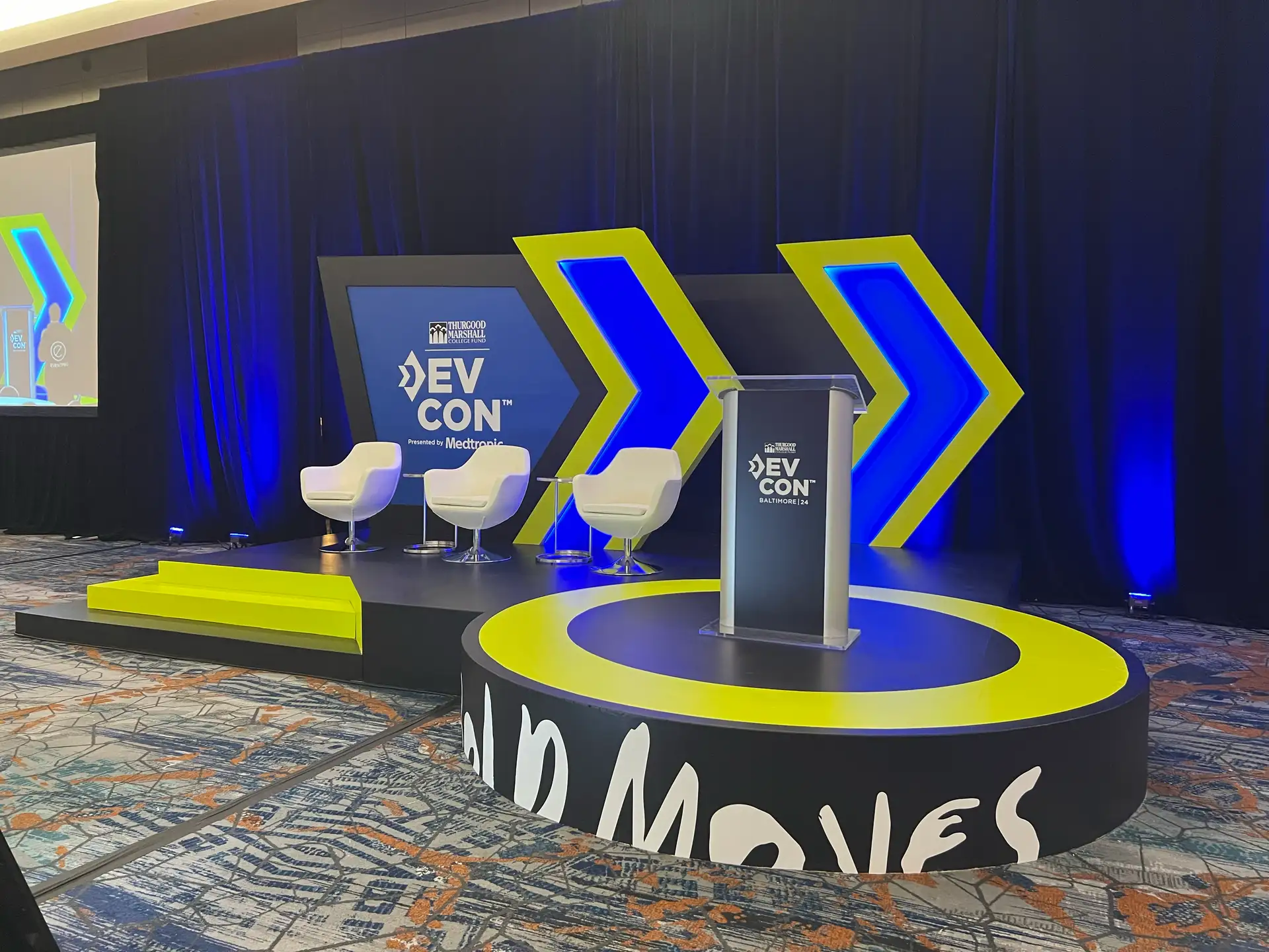 DevCon Conference 2024 main stage with Bold Moves circular riser, chevron arrow props, and branded scenic backdrop, Hilton Baltimore, EventPro