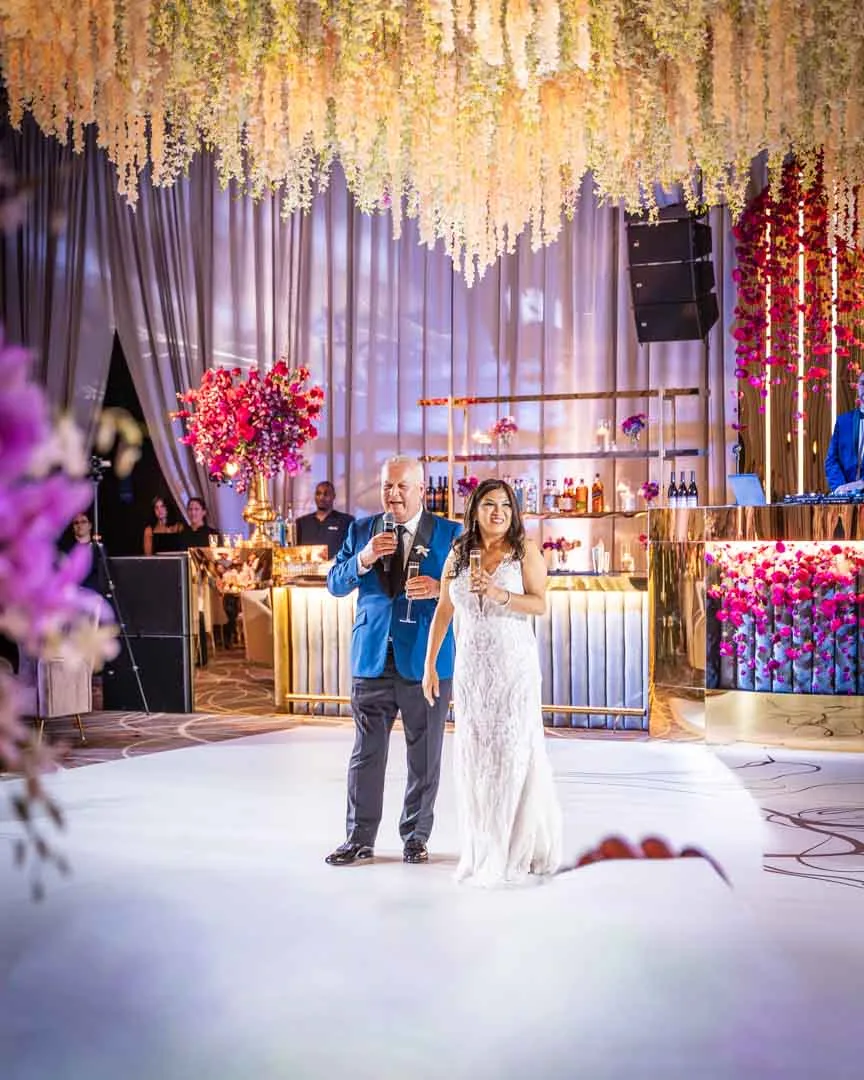 Kam and Kay on the dance floor at Four Seasons Baltimore wedding reception by EventPro custom dance floor graphic, hanging floral ceiling, lit bar backdrop behind couple