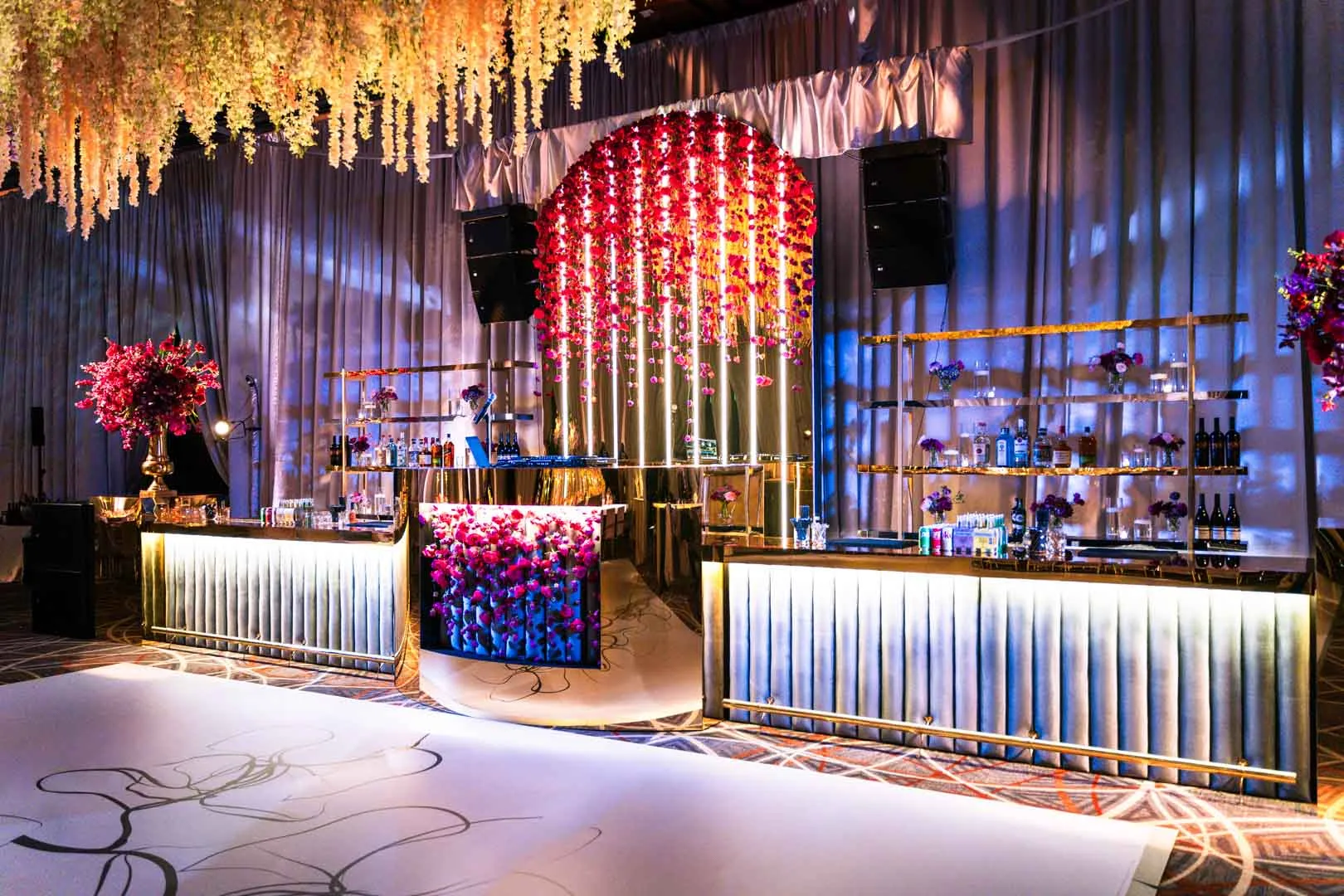 Custom bar fabricated by EventPro for Kam and Kay wedding at Four Seasons Baltimore by gold mirrored face, integrated floral front panel, lit column backdrop