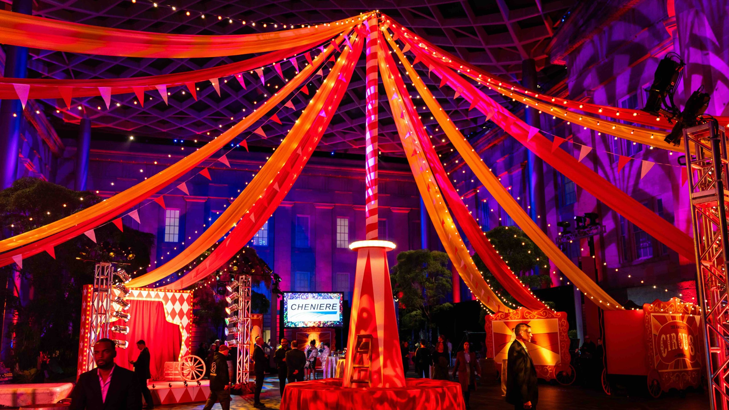 Full circus and carnival transformation of the National Portrait Gallery Atrium for the Kings Dinner DC Mardi Gras 2025, custom freestanding center pole, fabric tent canopy, and Side Show stage by EventPro Washington DC