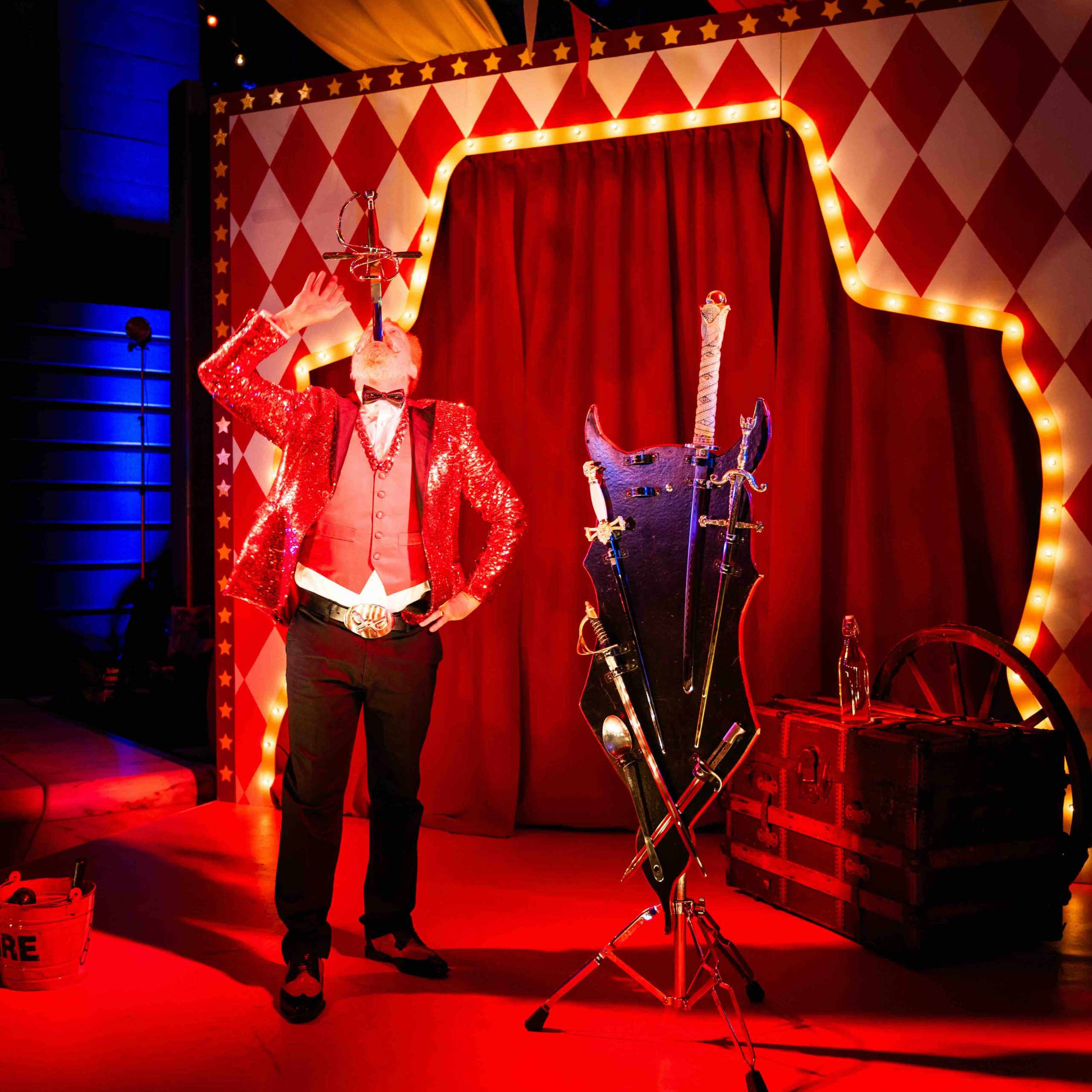 Sideshow performer in custom environment, harlequin backdrop with marquee arch and sword act props, Kings Dinner DC Mardi Gras 2025, EventPro Washington DC