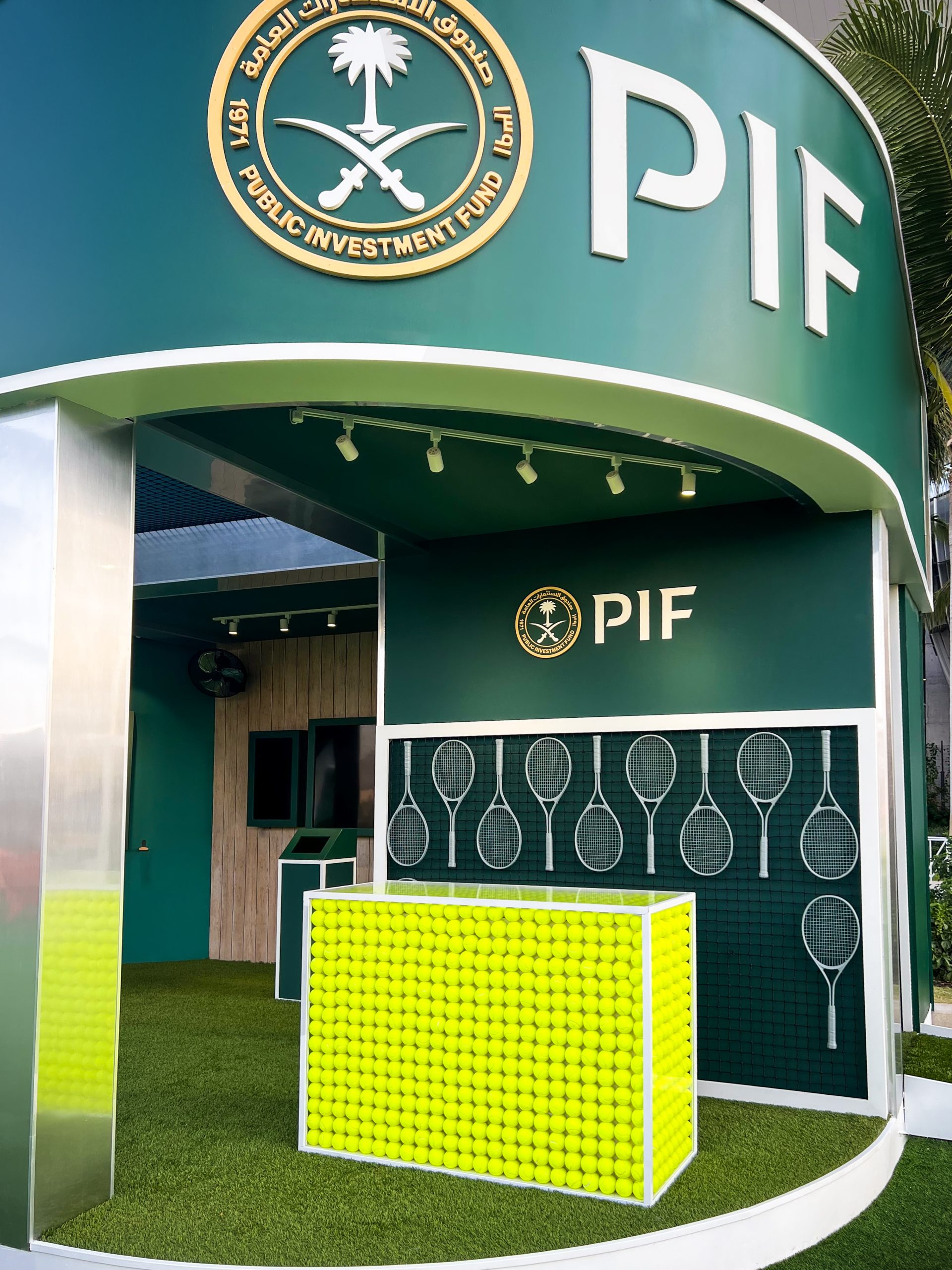 Close-up of PIF pavilion curved green exterior, gold medallion seal, bold PIF wordmark, and custom-fabricated oversized tennis racket sculpture, EventPro Miami Open 2025