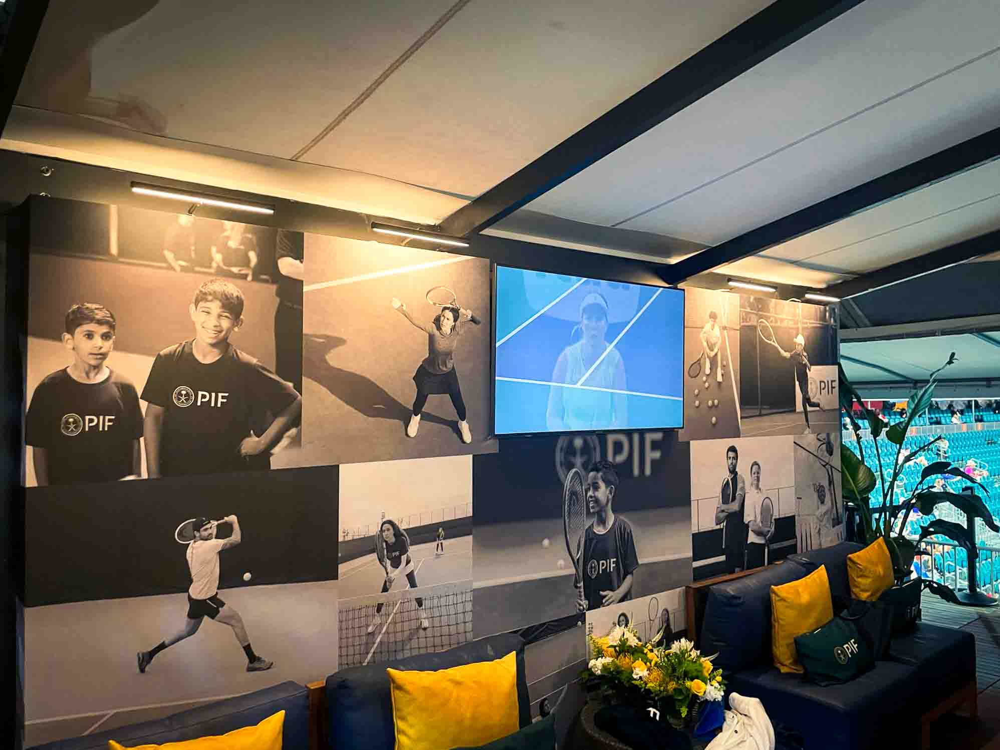 PIF hospitality lounge interior, custom navy sofas with gold throw pillows and large-format black-and-white tennis photo wall, EventPro brand activation Miami Open 2025