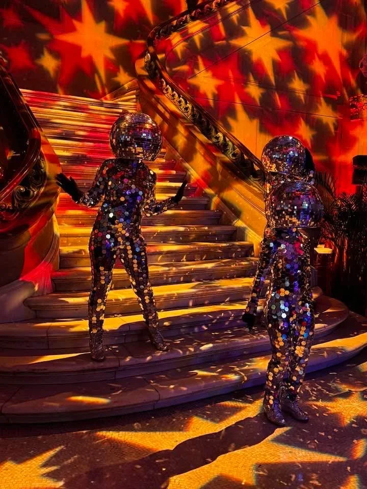 Mirror suit performers on grand staircase with star burst projection lighting — EventPro