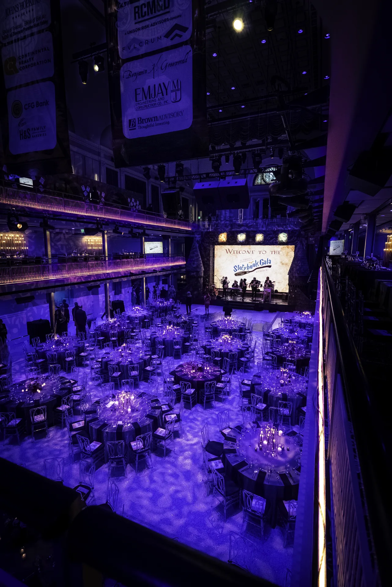 Wide HDR view of the M&T Bank Exchange ballroom, Storybook Gala welcome screen, castle stage set at far end, full table setup, purple lighting, EventPro production Baltimore