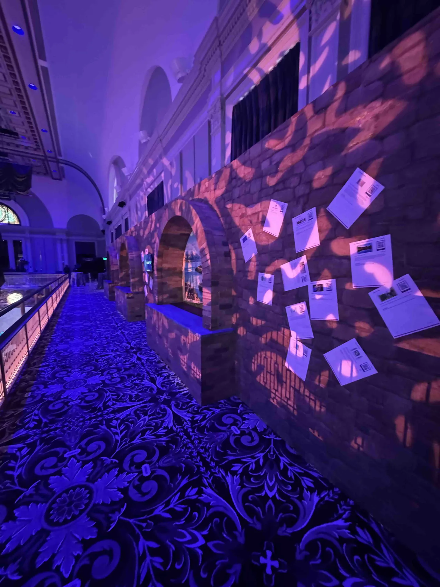 Castle corridor with stone arch wall, auction items mounted in niches, purple wash and projected pattern lighting, Mt. Washington Pediatric Hospital Storybook Gala, EventPro