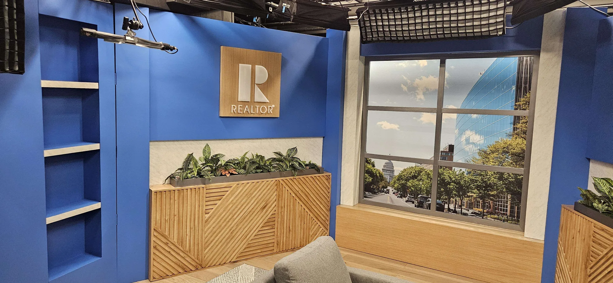 NAR studio set side view showing built-in shelving unit, REALTOR logo panel, custom credenza with planter, and printed DC cityscape window backdrop, EventPro Washington DC