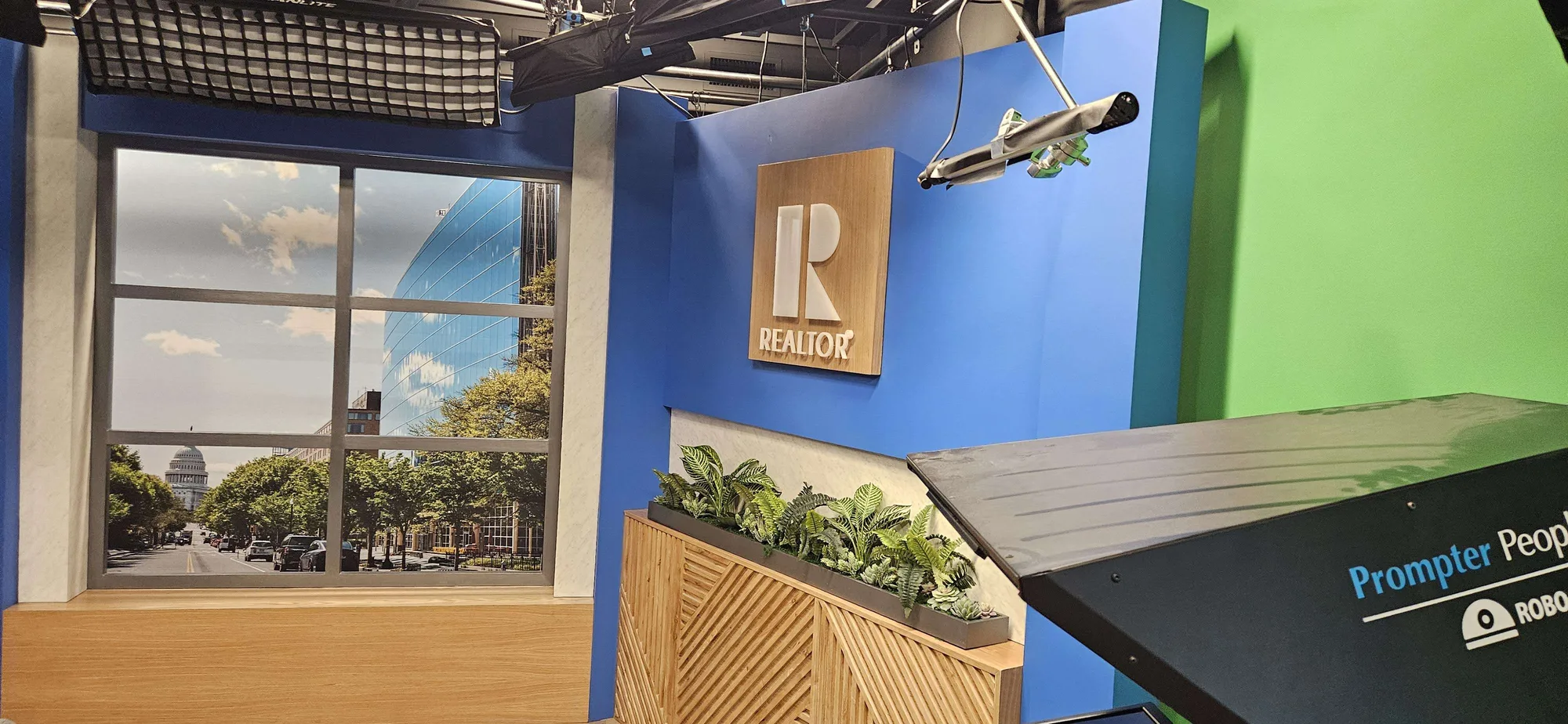 NAR broadcast studio set full context view showing custom set build with REALTOR branded panels, printed city backdrop, and production studio environment, EventPro DC 2025