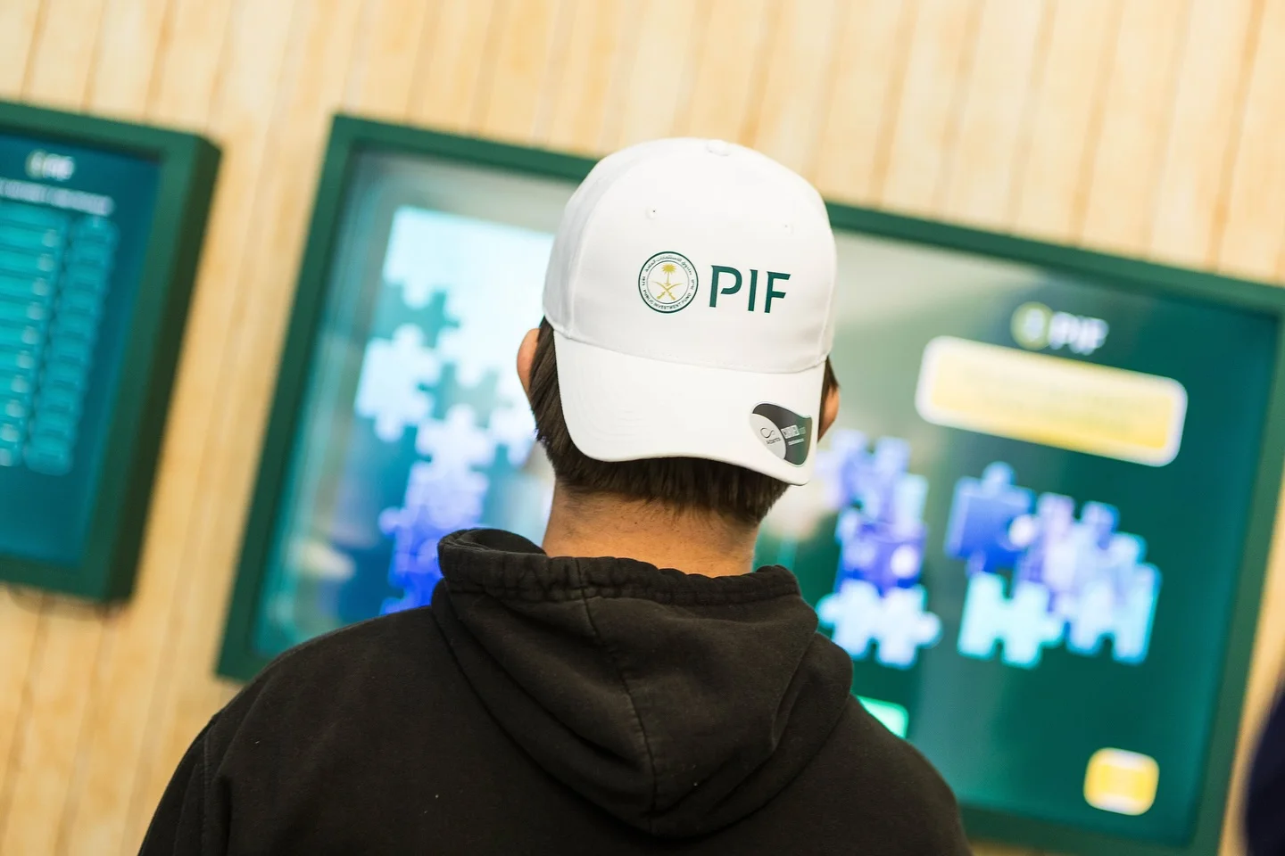 Attendee engaging with PIF interactive screen inside the BNP Paribas Open pavilion, custom framed display on wood slat wall, EventPro