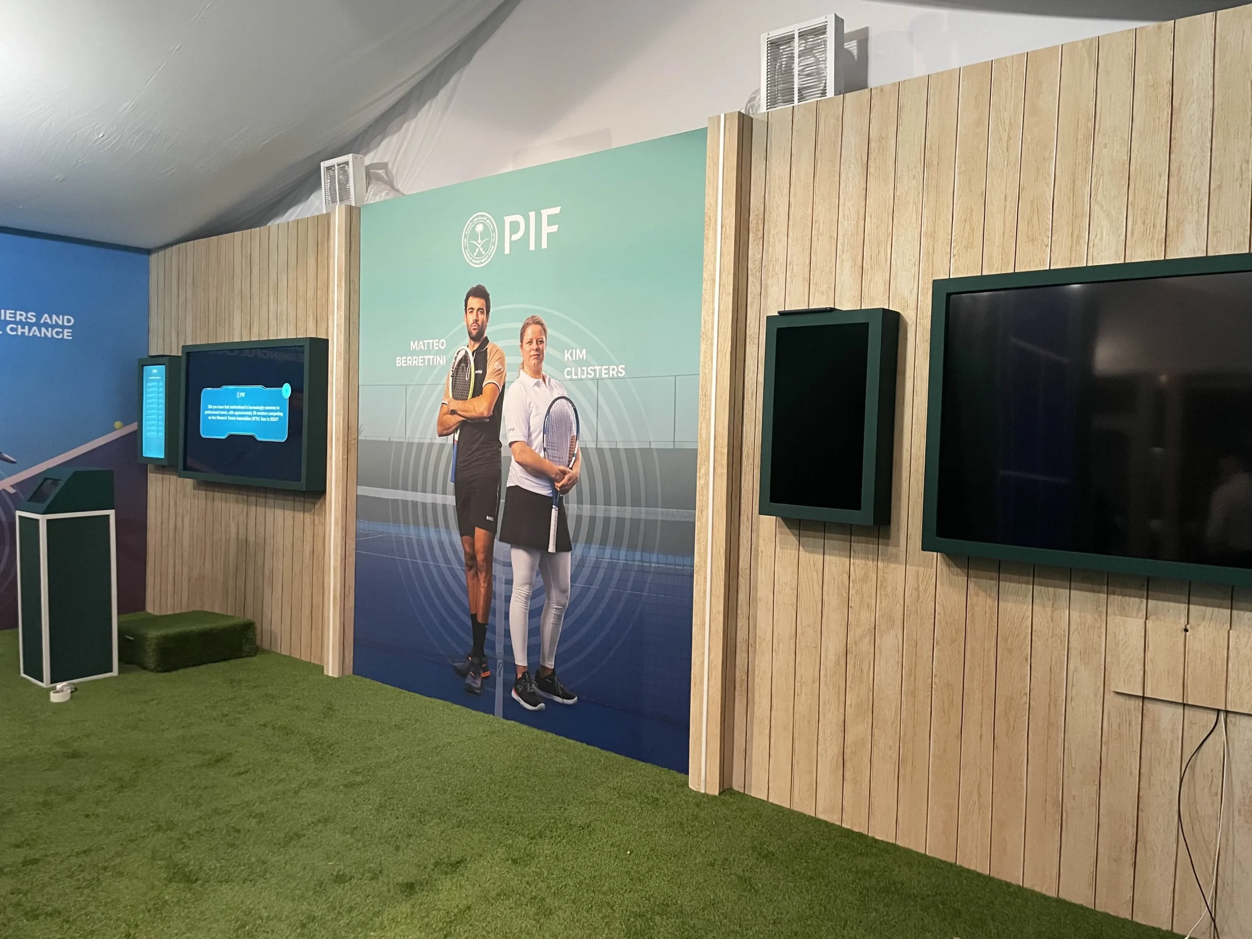 PIF pavilion interior overview, custom wood slat walls, large-format graphics, mounted display screens, turf flooring, Indian Wells Tennis Garden