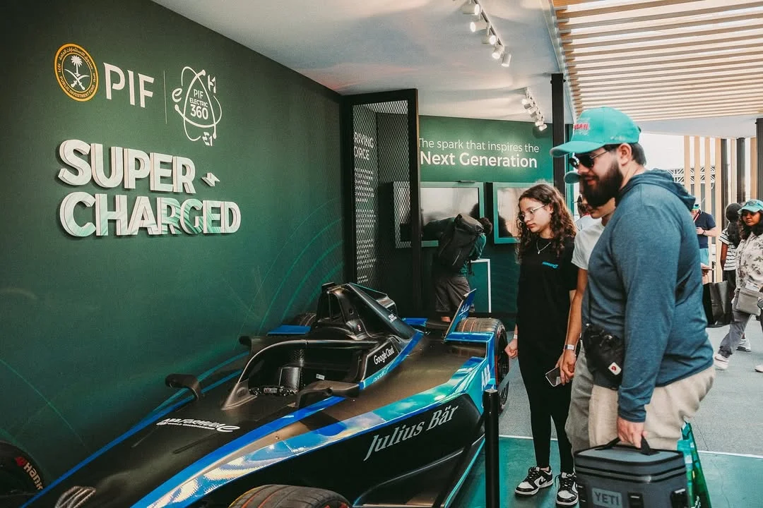 Visitors alongside Formula E race car display inside PIF Super Charged pavilion, Miami Formula ePrix 2025, EventPro