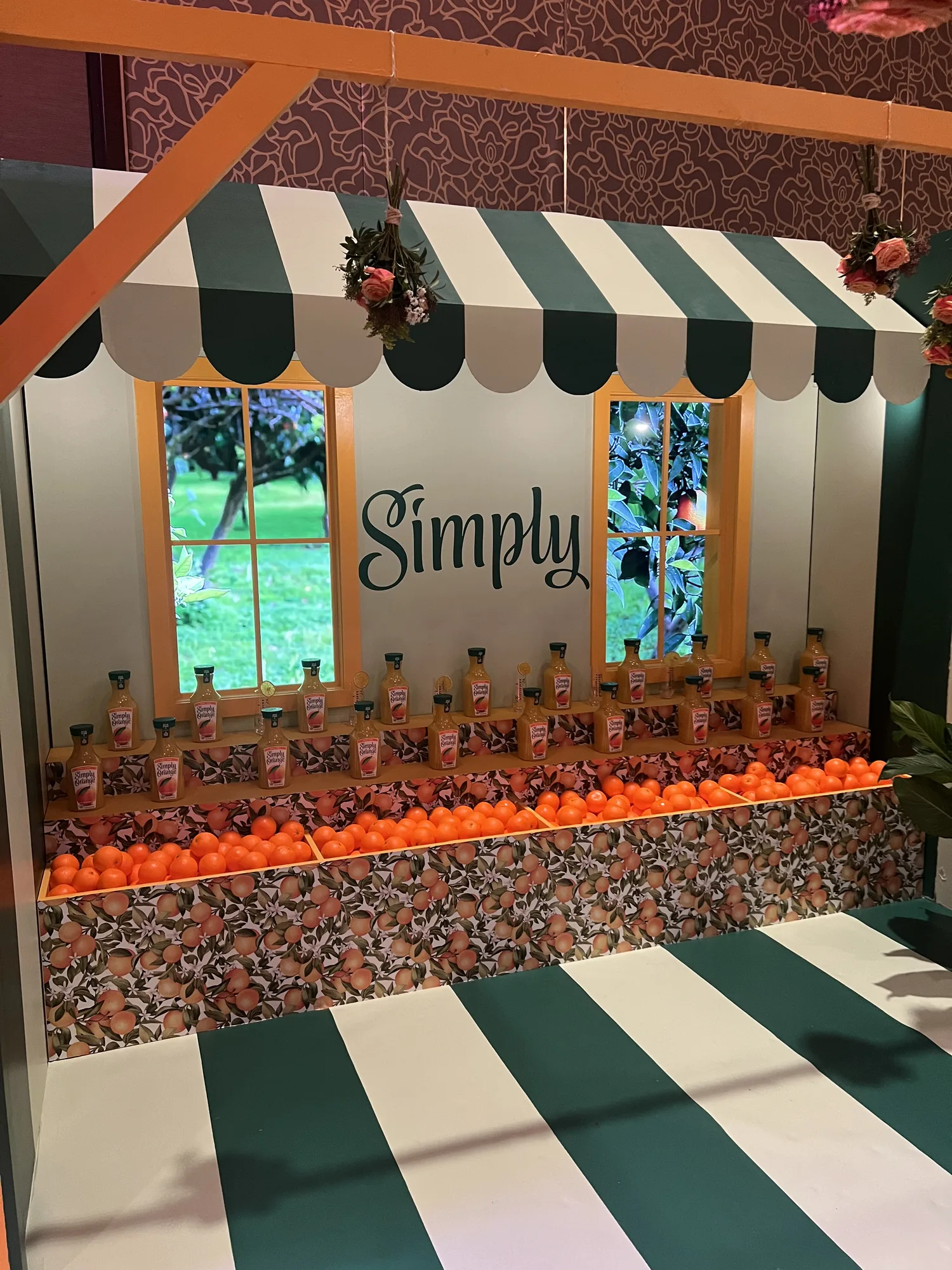 Simply branded market stall counter with orange display and juice bottles under green striped awning, Hard Rock Miami Gardens, EventPro