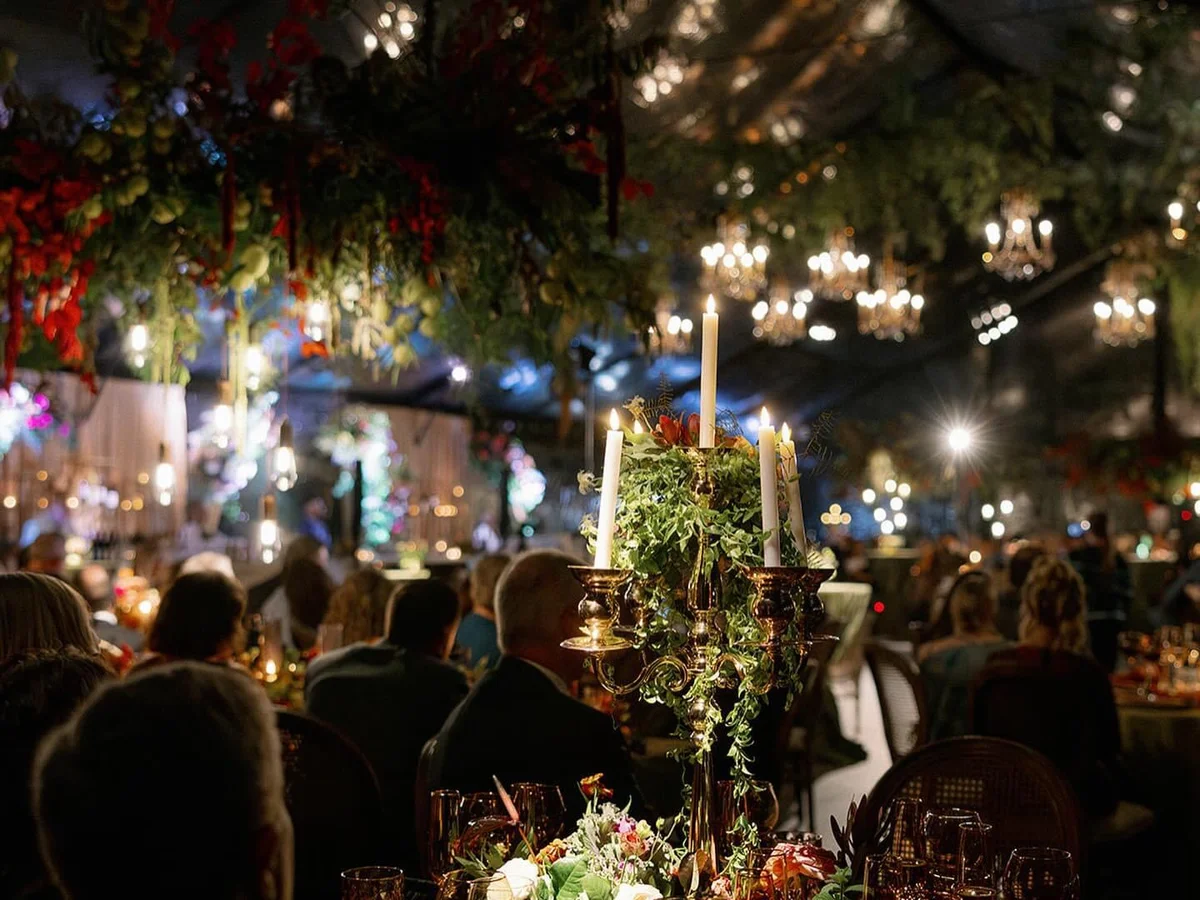 Pin spotted centerpieces and chandeliers at tented wedding reception by Event Pro