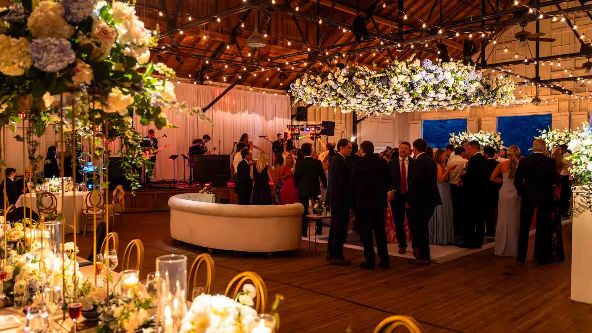 Wedding reception in barn venue with string lights, florals, and live band — EventPro productions